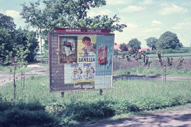 BA-2715: „Grabstede: Plakattafel mit Werbeplakaten von Glanzit, Sanella, Lux und Gold Dollar“