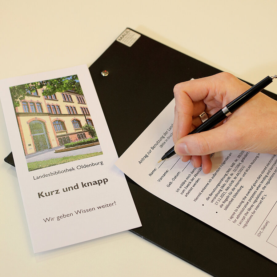 Eine Hand füllt ein Anmeldeformular aus. Daneben eine Informationsbroschüre mit dem Titel "Kurz und knapp"