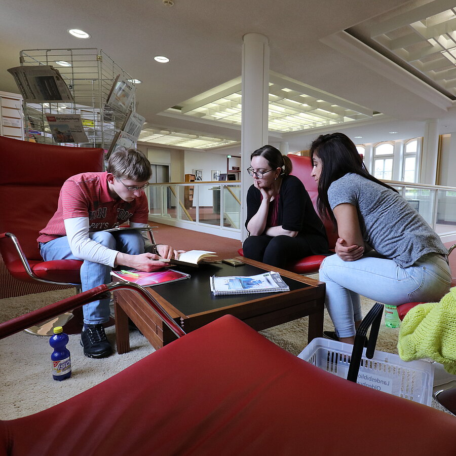 Eine Schülergrusse sitzt in den roten Ledersitzen auf Ebene 3 und arbeitet zusammen.