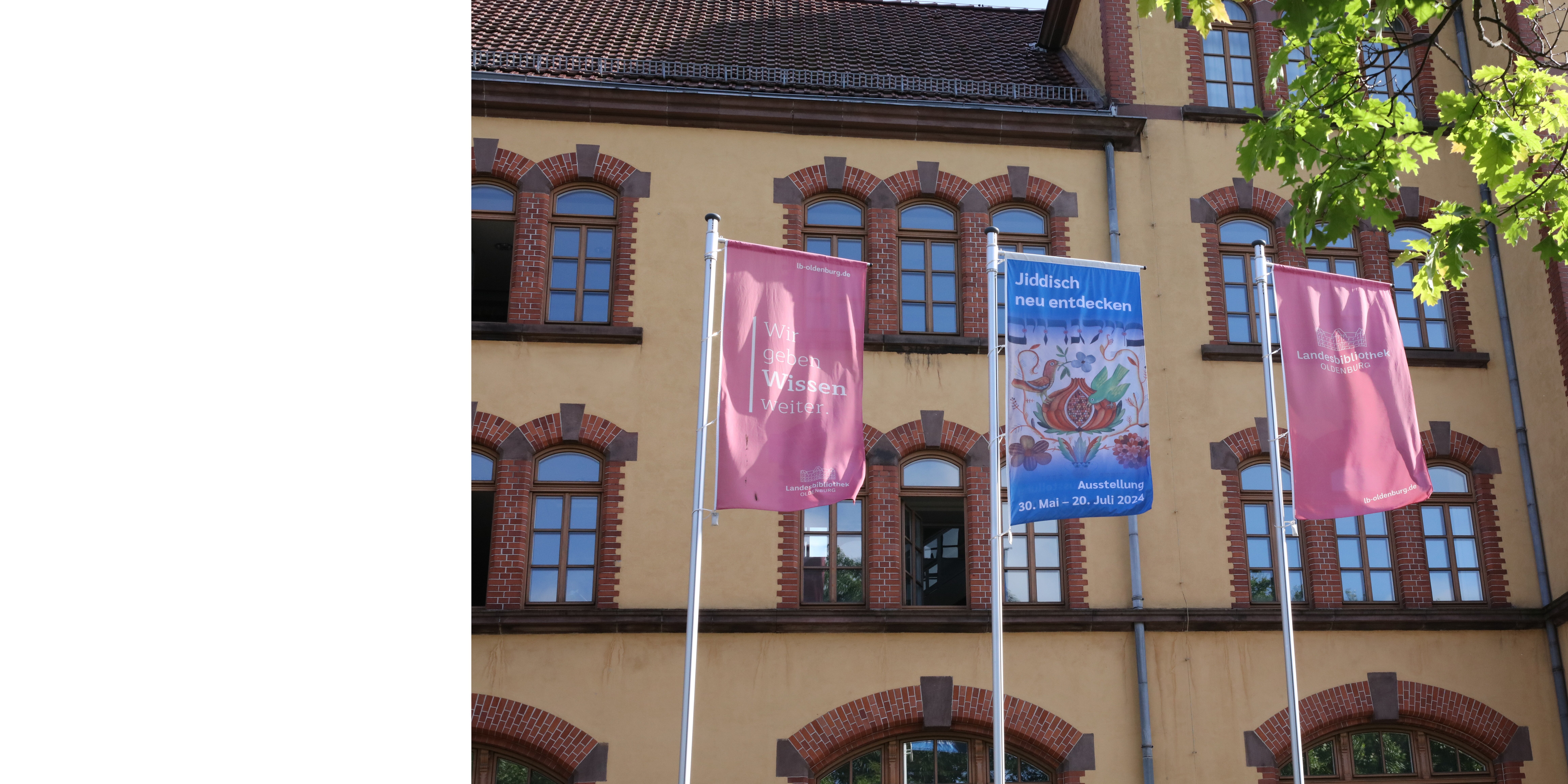 Fahnenmäste der Landesbibliothek Oldenburg. Links und rechts Fahnen mit dem Logo der LBO. In der Mitte Fahne der Ausstellung "Jiddisch neu entdecken".