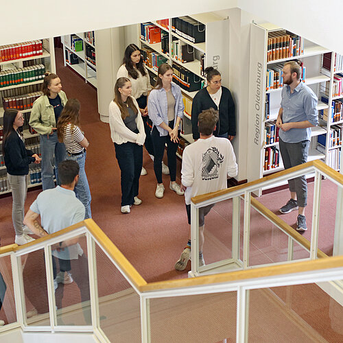 Ein Kollege führt eine Gruppe interessierter Studierender durch das Lern- und Informationszentrum.