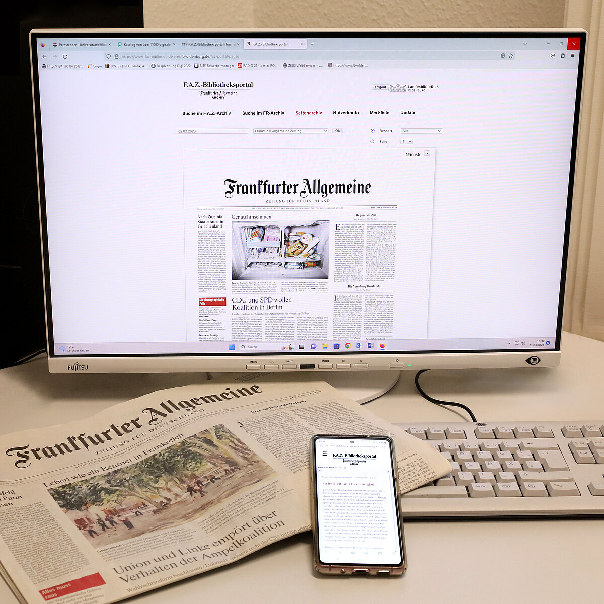 Ein Monitor zeigt das F.A.Z.-Bibliotheksportal mit einer digitalen Zeitungsausgabe. Im Vordergrund eine gedruckte Ausgabe, ein Smartphone mit dem Bibliotheksportal und eine Tastatur.