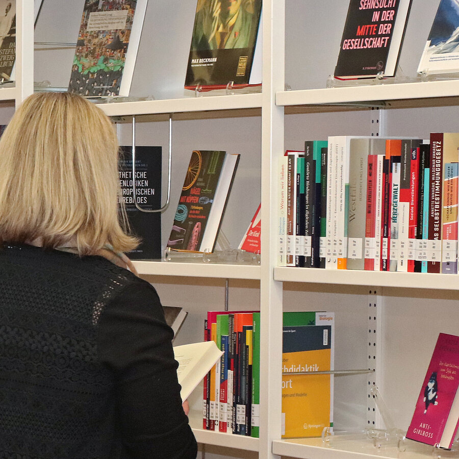 Eine Frau schaut sich Bücher aus dem Neuerwerbungsregal an.