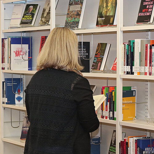 Eine Nutzerin steht vor dem Bücherregal mit Neuerscheinungen.