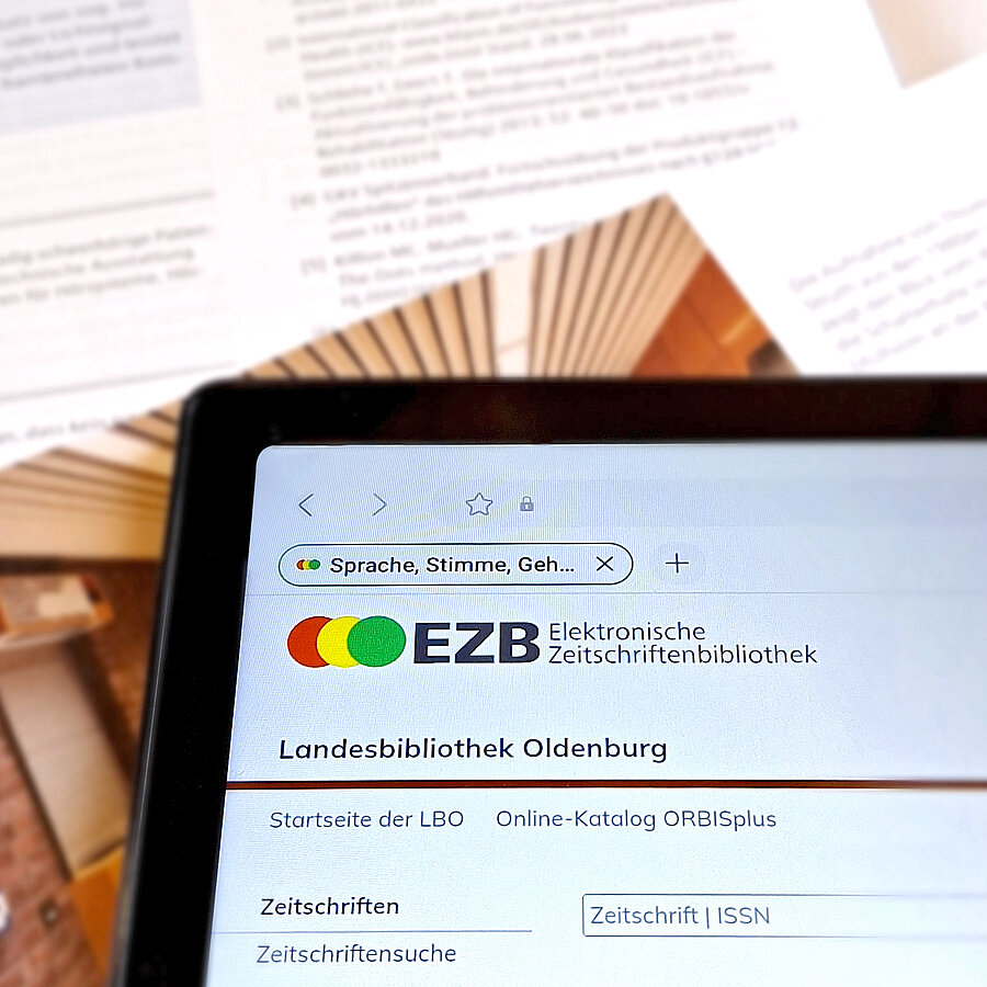 Tablet mit der Startseite der Elektronischen Zeitschriftenbibliothek (EZB) auf einem Stapel von Fachzeitschriften.